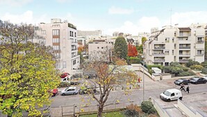 Un quartier résidentiel composé d’immeubles à plusieurs étages, d’un parking rempli de voitures et d’arbres aux feuilles d’automne.