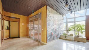 Un hall d’entrée spacieux avec un plafond en bois, une porte d’entrée en verre et une fresque murale.