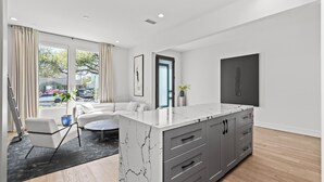 A modern kitchen with a marble countertop, grey cabinets, and a view of the outside. - Luxury 4-bedroom house in a family-friendly Houston neighborhood (Houston)