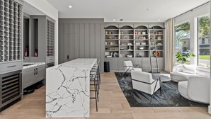 A modern kitchen with a marble island, grey cabinetry, and a large window. - Luxury 4-bedroom house in a family-friendly Houston neighborhood (Houston)