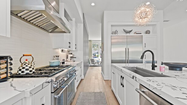 A modern kitchen with a central island, stainless steel appliances, and a view into the dining area. - Luxury 4-bedroom house in a family-friendly Houston neighborhood (Houston)