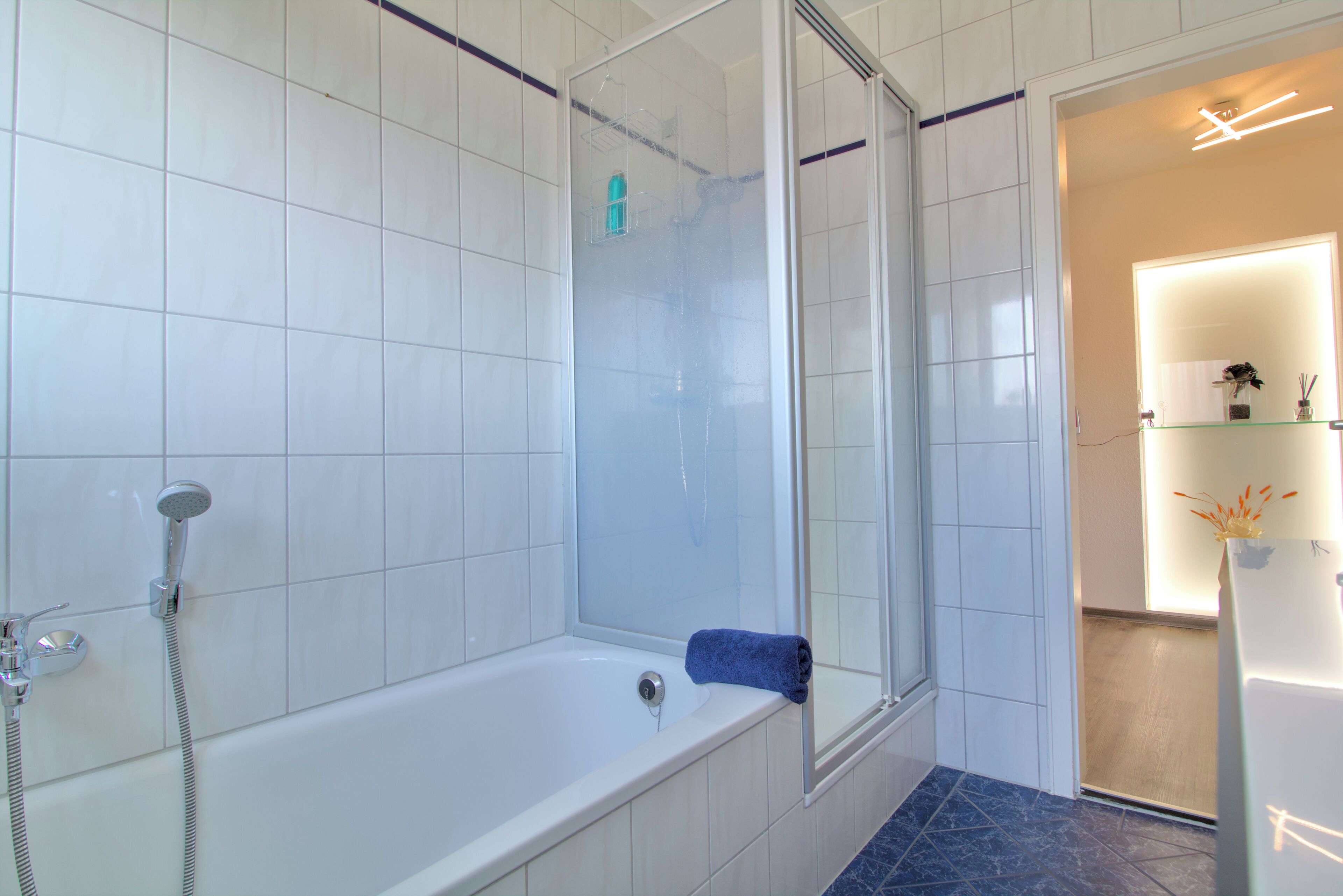Un baño con bañera, ducha y zona de ducha con mampara de vidrio.