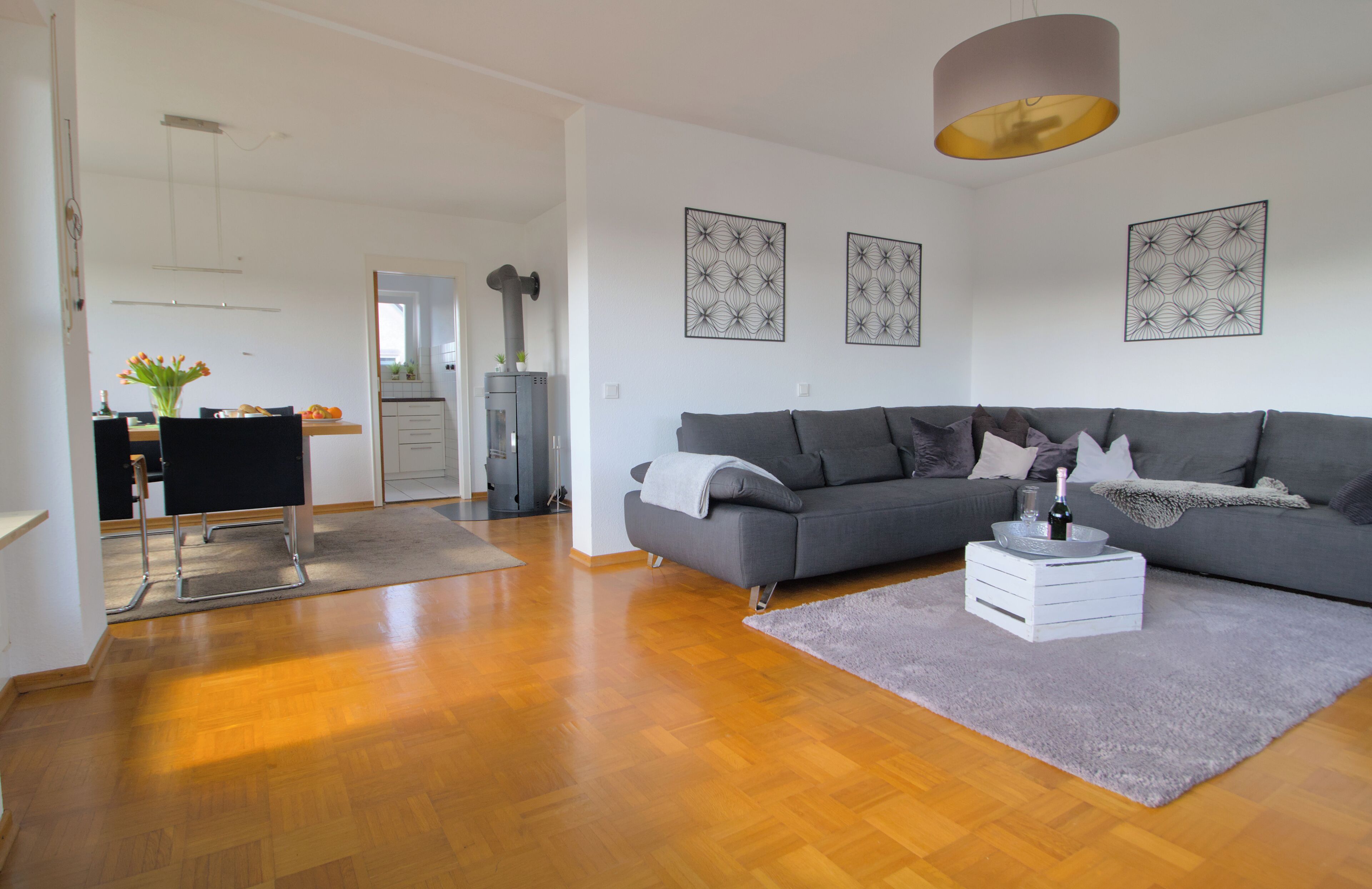 Ein modernes Wohnzimmer mit grauem Sofa, Couchtisch und Essbereich mit Stuhl und Tisch.