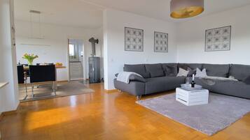 Ein modernes Wohnzimmer mit grauem Sofa, Couchtisch und Essbereich mit Stuhl und Tisch.