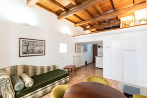 Una habitación con sofá, mesa de comedor y zona de cocina.