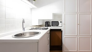 Een keuken met een spoelbak, fornuis, magnetron en kastjes.