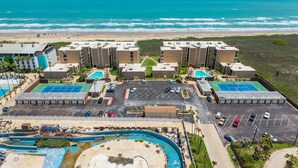 Um hotel à beira-mar com vários edifícios, piscina e estacionamento.