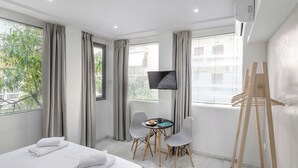Ein Hotelzimmer mit einem Bett, einem Schreibtisch mit zwei Stühlen, einem Flachbildfernseher und einem Holzeasel.