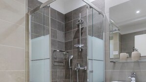 Ein modernes Badezimmer mit einer gläsernen Duschkabine, einem weißen Waschbecken und einem Spiegel darüber.