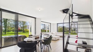 Een modern interieur met een eethoek, een bank en een spiltrap.