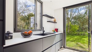 Een moderne keuken met een groot raam, een zwart aanrecht en een schaal met fruit.