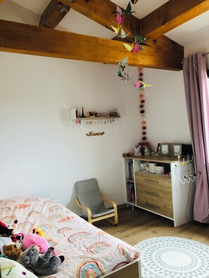 Ein Kinderzimmer mit Bett, Stuhl, Schreibtisch und Bücherregal.