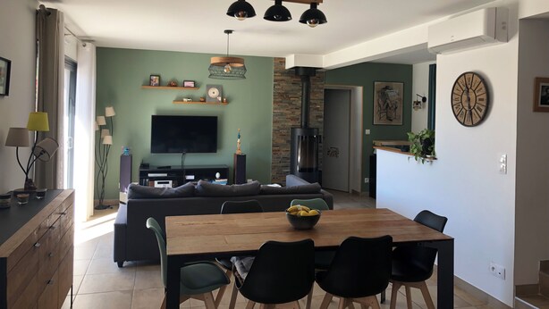 A modern living room with a flat-screen TV, wooden dining table, and black chairs. - House with swimming-pool in Luberon (Lauris)