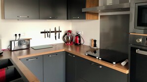 A modern kitchen with dark cabinetry, a built-in oven, a microwave, and a coffee maker. - House with swimming-pool in Luberon (Lauris)