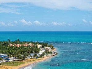 A coastal view with buildings, palm trees, and a beach. - NEW! Steps to the Beach, Pool, AC, View! Close to Attractions (Luquillo)