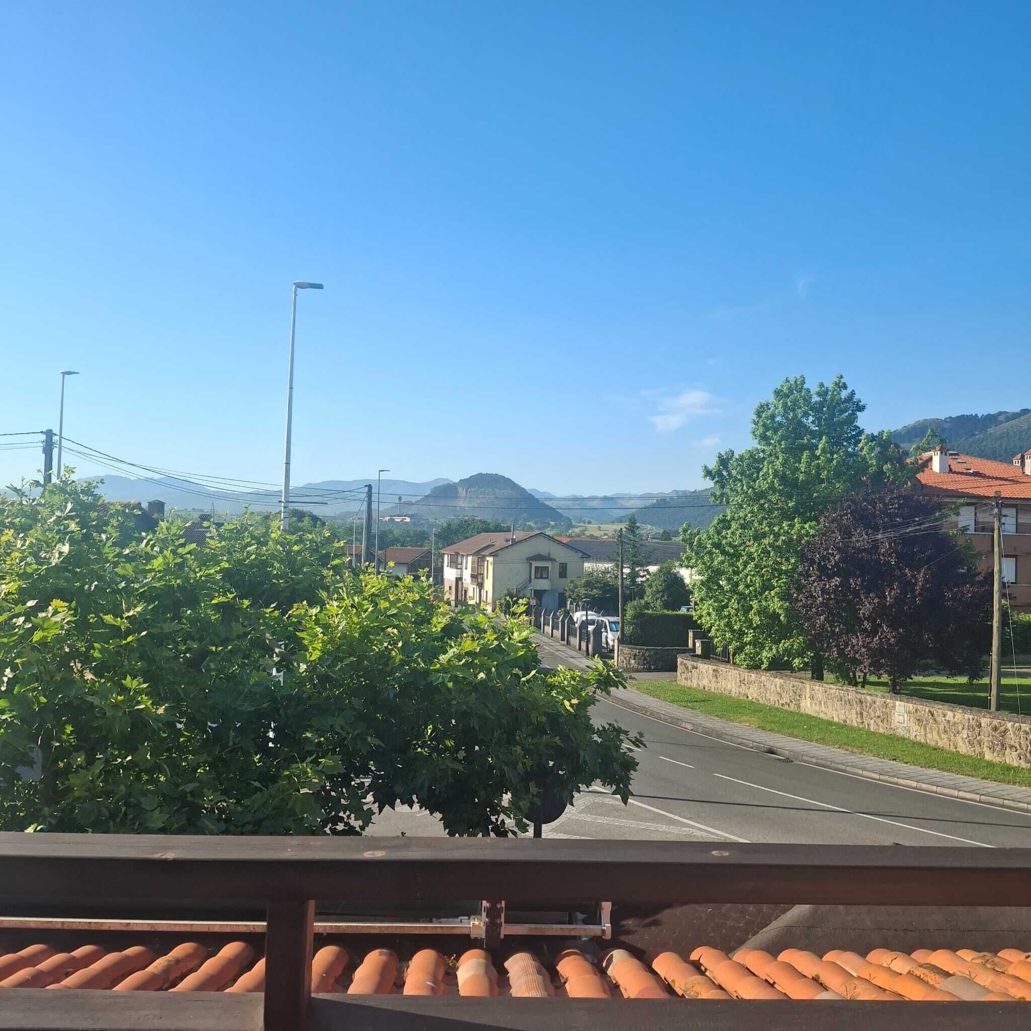 Una calle con casas, cielo despejado y montañas a lo lejos.