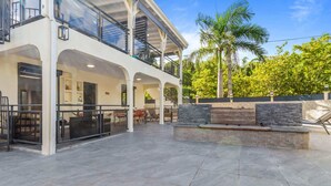 A modern two-story building with a covered outdoor patio, stone walls, and a palm tree in the background. - Résidence Dorée - Seven Bedroom Villa, Sleeps 14 (Sainte-Anne)