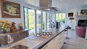 Una cocina moderna con una isla grande, pileta de acero inoxidable y vistas al exterior.