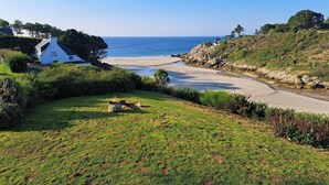 Un paisaje costero con un edificio blanco, una zona verde y una vista despejada del océano.