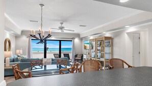 A modern living room with a dining area, large windows with a view, and a ceiling fan. - 🏖️Stunning Gulf Views | Pool | Aegean 220🏖️ (Destin)