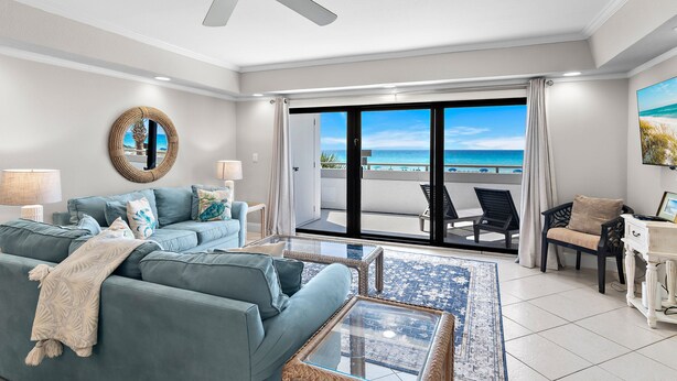 A living room with a sofa, coffee table, and a view of the ocean through large sliding doors. - 🏖️Stunning Gulf Views | Pool | Aegean 220🏖️ (Destin)