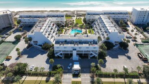 An aerial view of a hotel with a central pool, surrounded by parking and greenery, with a beach in the background. - 🏖️Stunning Gulf Views | Pool | Aegean 220🏖️ (Destin)
