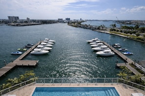 Un puerto deportivo con barcos amarrados, una piscina y un paisaje urbano al fondo.