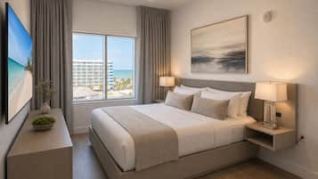 Una habitación de hotel con una cama grande, vistas a la playa, un cuadro en la pared y un detector de incendios.
