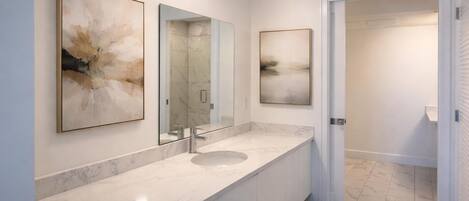 A modern bathroom with a marble sink, two wall-mounted mirrors, and abstract artwork.