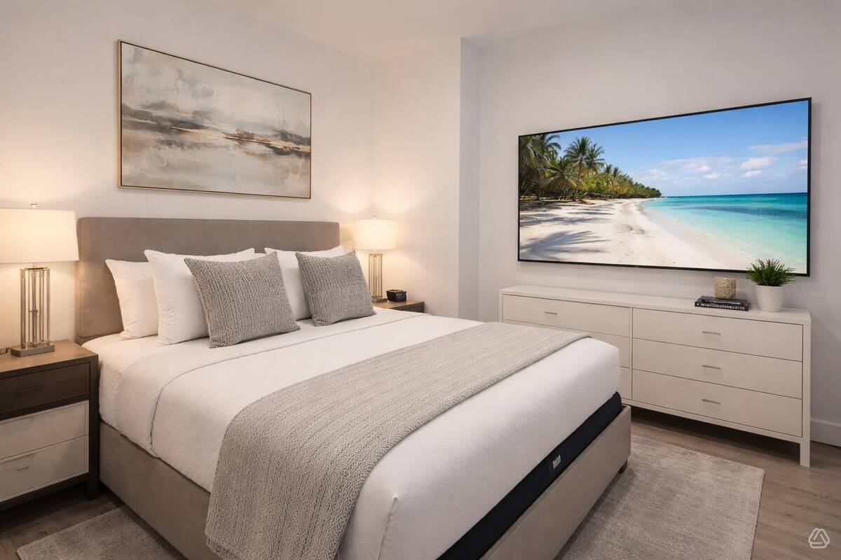 Un dormitorio moderno con una cama grande, mesitas de noche, un tocador, un aparador, un televisor de pantalla plana y un cuadro en la pared.