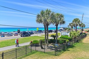 A coastal road with a pedestrian path, palm trees, and a sign for 'Blue Surf.' - 🏖️Gulf Views - Pool - Across from Beach - Blue Surf 1🏖️ (Miramar Beach)