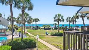 A resort with a pool, palm trees, and a view of the ocean. - 🐚Gulf + Pool Views | Pet Friendly | Blue Surf 19🐚 (Miramar Beach)
