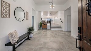 Un intérieur moderne avec un banc, une plante en pot, un miroir et un escalier menant à une autre pièce.