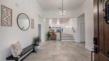 Un intérieur moderne avec un banc, une plante en pot, un miroir et un escalier menant à une autre pièce.