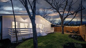 Une maison avec une terrasse, un foyer extérieur et des guirlandes lumineuses.