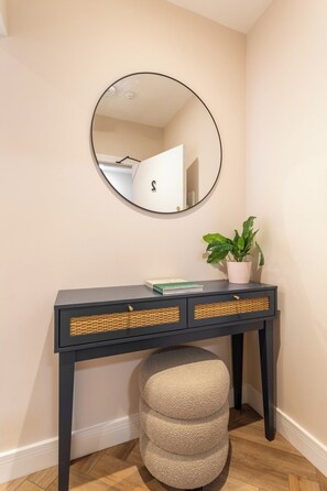 A dark wooden console table with wicker baskets, a potted plant, and a book. - The Brighton Bliss - Sleeps 7 (Brighton)