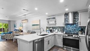Eine moderne Küche mit weißen Schränken, Edelstahlgeräten und einer blauen Mosaikrückwand.