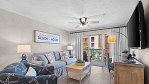 A living room with a sofa, coffee table, and a TV. There's a sign that says "Welcome to the Beach House." - 🌊Free Beach Chairs🐚Pet Friendly | Steps to Beach | Pool | Ciboney 3008☀️ (Miramar Beach)