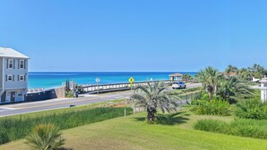 A coastal road with a pedestrian crossing sign, a white building, and a view of the ocean. - 🌊Free Beach Chairs🐚Pet Friendly | Steps to Beach | Pool | Ciboney 3008☀️ (Miramar Beach)