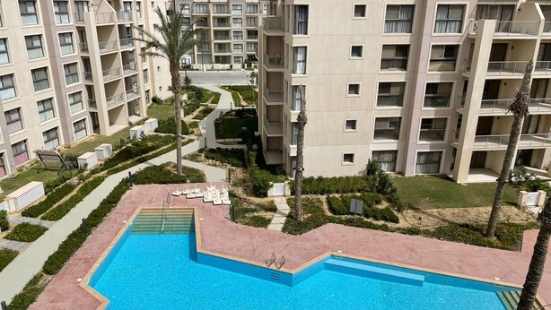 A residential building complex with a central swimming pool, multiple balconies, and a well-maintained garden area. - Chalet 2 Bedrooms Marina2-16j - 403 (El Alamein)