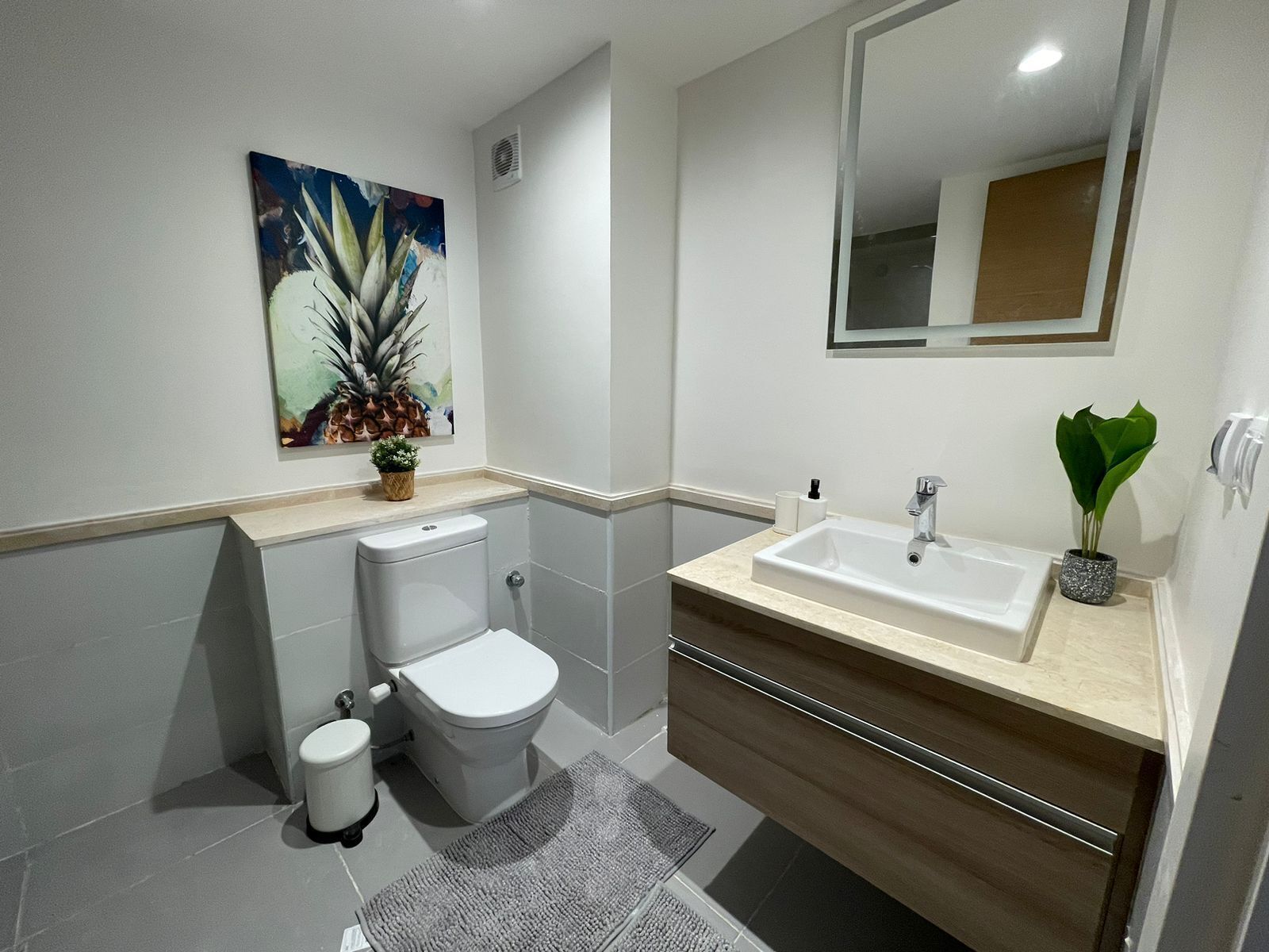 A modern bathroom with a toilet, sink, and mirror.
