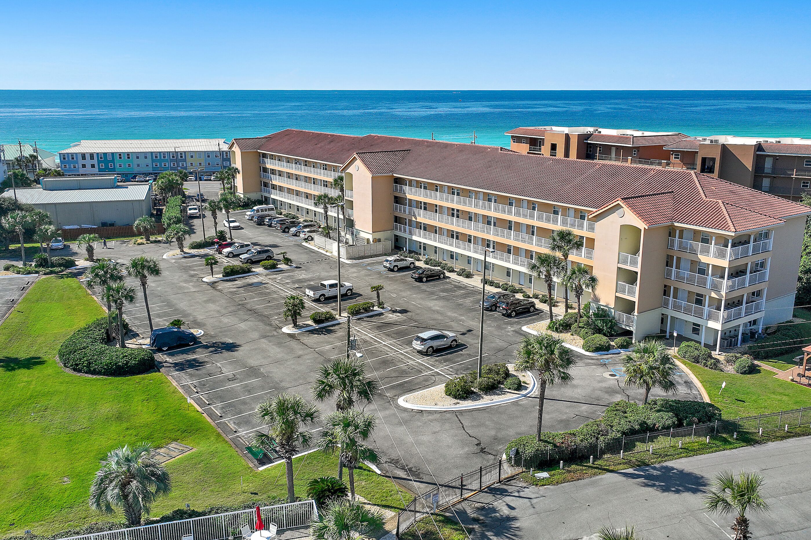 Een hotel met meerdere verdiepingen, een parkeerplaats en uitzicht op de oceaan.