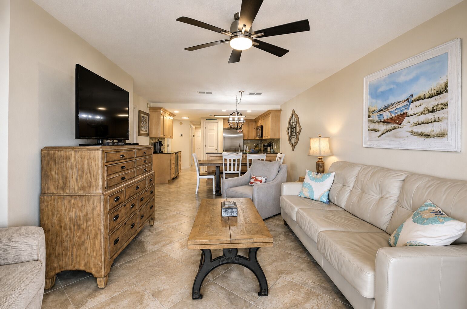 A living room with a TV, wooden cabinet, leather sofa, and a dining area with a table and chairs.