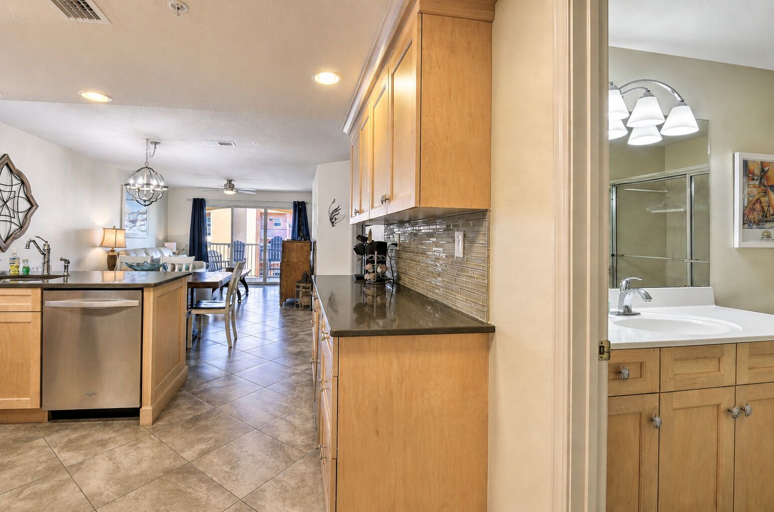 A modern kitchen with wooden cabinets, a central island, and a dining area with a view.