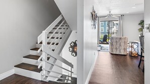 Een trap met witte leuningen en donkere houten treden, een plafondventilator en uitzicht op een balkon met tuinmeubels.
