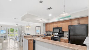A modern kitchen with a central island, wooden cabinets, and a 'WELCOME TO PARADISE' sign.