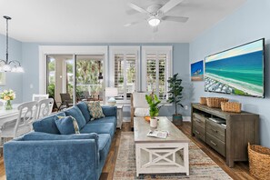 A living room with a sofa, coffee table, and a television on a wall. - 🏖️Sandestin | Pool+Hot Tub | Resort Tram | Pilot House 322🐚 (Miramar Beach)