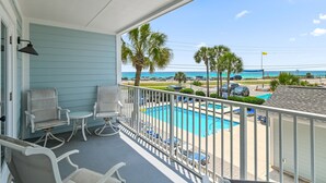 Ein Balkon mit Pool, Stühlen und Blick auf den Strand.