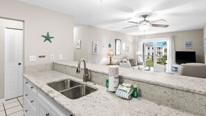 Cucina con lavello in acciaio inossidabile, ventilatore a soffitto e zona pranzo con televisore.