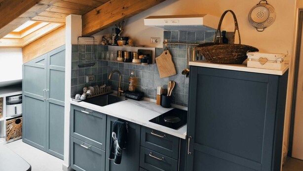 A kitchen with dark cabinets, a white countertop, a hanging pot rack, and a skylight. - Thumbelina House (Sapri)